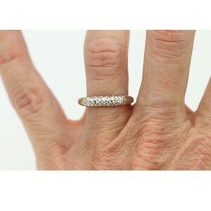 May include: A white gold band ring with a row of small round diamonds set in a channel setting.
