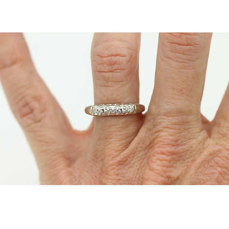 May include: A white gold band ring with a row of small round diamonds set in a channel setting.