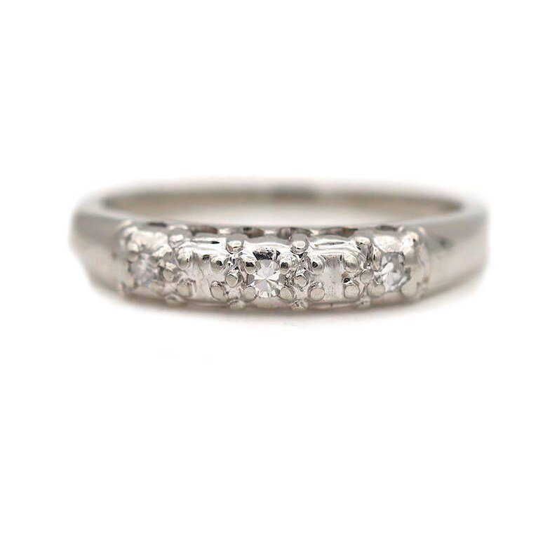 May include: A silver band with five small diamonds set in a row.