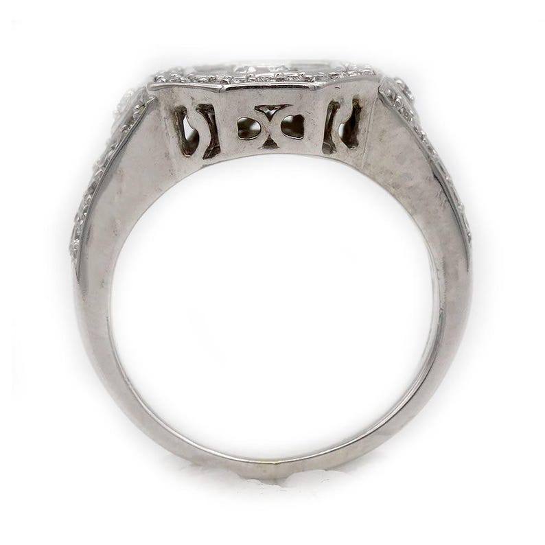 Pu&ograve; includere: Un anello color argento con una fascia larga e un intricato design traforato. La parte superiore dell'anello &egrave; incastonata con molteplici piccole pietre chiare e scintillanti disposte in un motivo geometrico che si estende lungo i lati.