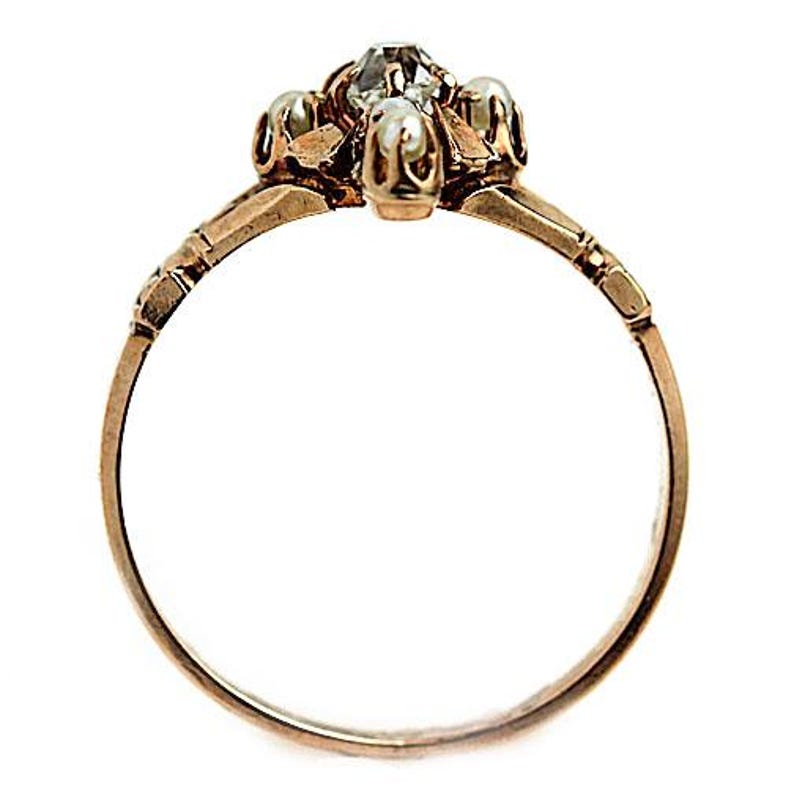 Puede incluir: Un anillo de oro con un diamante central y cuatro acentos de perla. El anillo est&aacute; engastado en un delicado dise&ntilde;o floral.