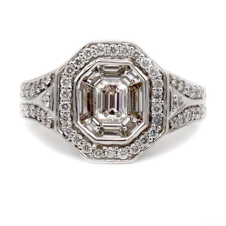Pu&ograve; includere: Un anello color argento con un diamante centrale taglio smeraldo circondato da un alone di diamanti rotondi pi&ugrave; piccoli. La fascia &egrave; divisa in due sezioni su ciascun lato, con ulteriori diamanti rotondi incastonati sulla superficie.