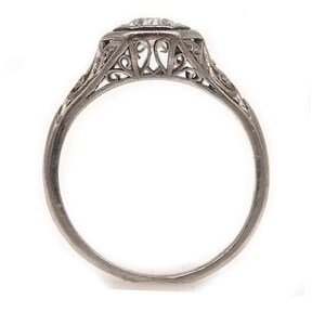 Puede incluir: Un anillo de compromiso de filigrana de plata con un diamante redondo y claro en el centro.