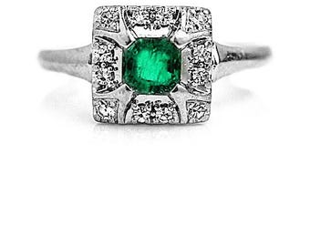 May include: A silver ring with a square emerald gemstone surrounded by smaller diamonds.