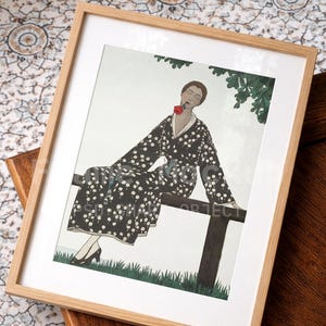 May include: A framed art print depicting a figure in a black and white polka dot robe, holding a red rose. The artwork is set against a white background, framed in light wood. The image is a vintage-style illustration.