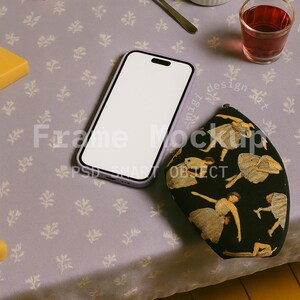 Può includere: Una scena di mockup con uno smartphone con schermo bianco, una pochette nera con un design di ballerina, formaggio, burro, un cucchiaio e un bicchiere di liquido rosso. Gli oggetti sono disposti su una superficie lavanda a motivi floreali.