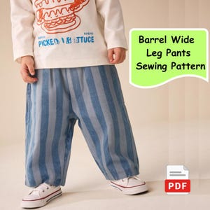 May include: Blue and white striped barrel wide leg pants. The pants are worn with a white long-sleeve shirt with a burger graphic and white sneakers. The image also includes a green rectangle with the text "Barrel Wide Leg Pants Sewing Pattern" and a PDF icon.