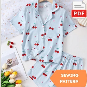 Peut inclure: Ensemble de pyjama bleu clair avec un motif de cerises. L'ensemble comprend une chemise boutonnée à manches courtes et un short assorti. La chemise a une poche poitrine. L'image comprend également une icône PDF et une bannière orange avec "SEWING PATTERN".