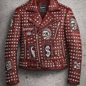 Full-length display of red studded biker jacket laid flat, showcasing hardware, zipper design, patches, and bold punk aesthetic.