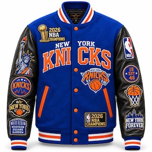 Op de afbeelding: Een blauwe varsity-jas met zwarte leren mouwen, voorzien van oranje en wit gestreepte geribbelde boorden. De voorzijde toont de tekst New York Knicks, een 2026 NBA Champions-patch en diverse geborduurde patches, waaronder het Vrijheidsbeeld, Madison Square Garden en basketbalmotieven.