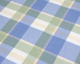 May include: A close-up of a fabric with a plaid pattern. The pattern features a grid of blue, green, white, and orange lines. The fabric has a soft, textured appearance, suggesting it may be used for clothing or home decor.