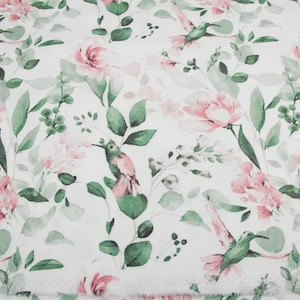 May include: White fabric with a watercolor floral pattern featuring pink roses, green leaves, and hummingbirds. The design has a soft, delicate aesthetic, suitable for various craft projects.