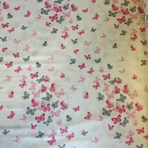 May include: White fabric with a repeating pattern of pink and grey butterflies. The fabric has the text "Design No. 9.20019" printed on the bottom edge.