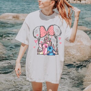 Stitch Angel castle shirt with Minnie ears and pink bow design Disney couple shirt with Stitch and Angel inspired characters pink Disney vacation tee with castle hearts and fireworks Minnie ears castle shirt with cute Stitch Angel graphic theme park outfit shirt with magical castle and pink bow Stitch and Angel Disney shirt for couple vacation outfit cute Disney lover gift shirt with castle and hearts design white Disney inspired graphic tee with Stitch Angel artwork