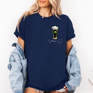 A woman wearing a navy blue t-shirt with a graphic of a beer mug and the text "Atria S" printed on it, along with a denim jacket.