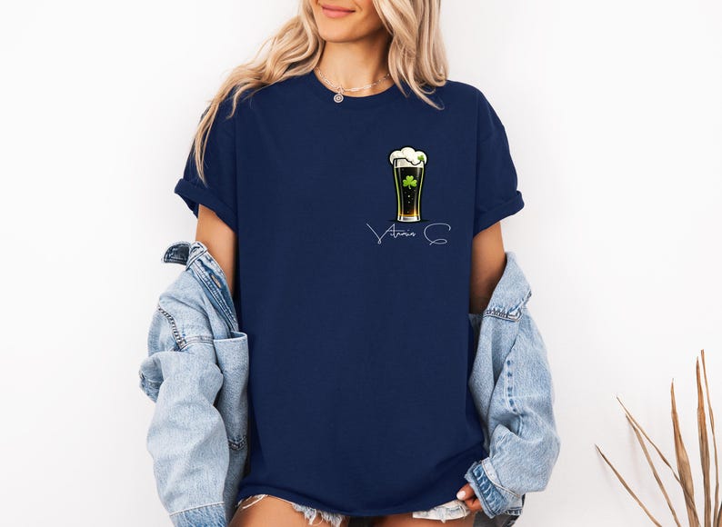 A woman wearing a navy blue t-shirt with a graphic of a beer mug and the text "Atria S" printed on it, along with a denim jacket.