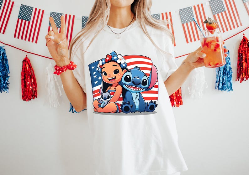 May include: White t-shirt featuring a graphic of Lilo and Stitch with an American flag background. The design includes Lilo, Stitch, and a small Stitch. The shirt is worn by a person holding a drink with a strawberry garnish.
