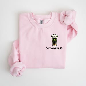 A pink sweatshirt with a graphic of a beer glass and the text "Vitamin G" printed on it.