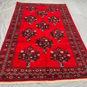 May include: A rectangular red rug with a repeating floral pattern. The rug features a central field of red with stylized floral motifs in shades of brown, blue, and white. The border is a darker red with geometric designs.