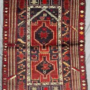 Peut inclure: Tapis rectangulaire avec un motif géométrique central rouge foncé et bleu marine. Le tapis présente une bordure avec des motifs répétitifs rouges, beiges et bruns. Le motif du tapis comprend des formes étoilées et géométriques.