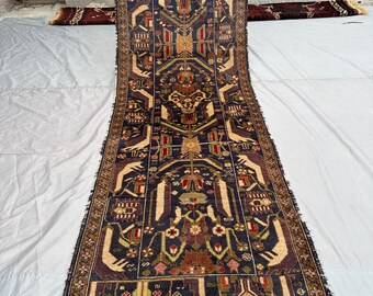 Könnte beinhalten: Ein langer, rechteckiger Teppich mit dunkelblauem Hintergrund und komplizierten geometrischen Mustern in Beige, Rot und Braun. Der Teppich hat ein zentrales Design mit sich wiederholenden Motiven und einen detaillierten Rand. Der Teppich wird von einer Person gehalten.