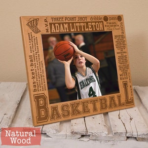 May include: A wooden picture frame with a basketball theme. The frame has a cutout of a basketball hoop and the word "basketball" is engraved in large letters. The frame is designed to hold a 4x6 inch photo. The text "Adam Littleton" is engraved on the frame.