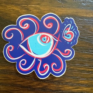 May include: A blue and red eye with a white swirl design. The eye is surrounded by a blue and red swirl pattern.