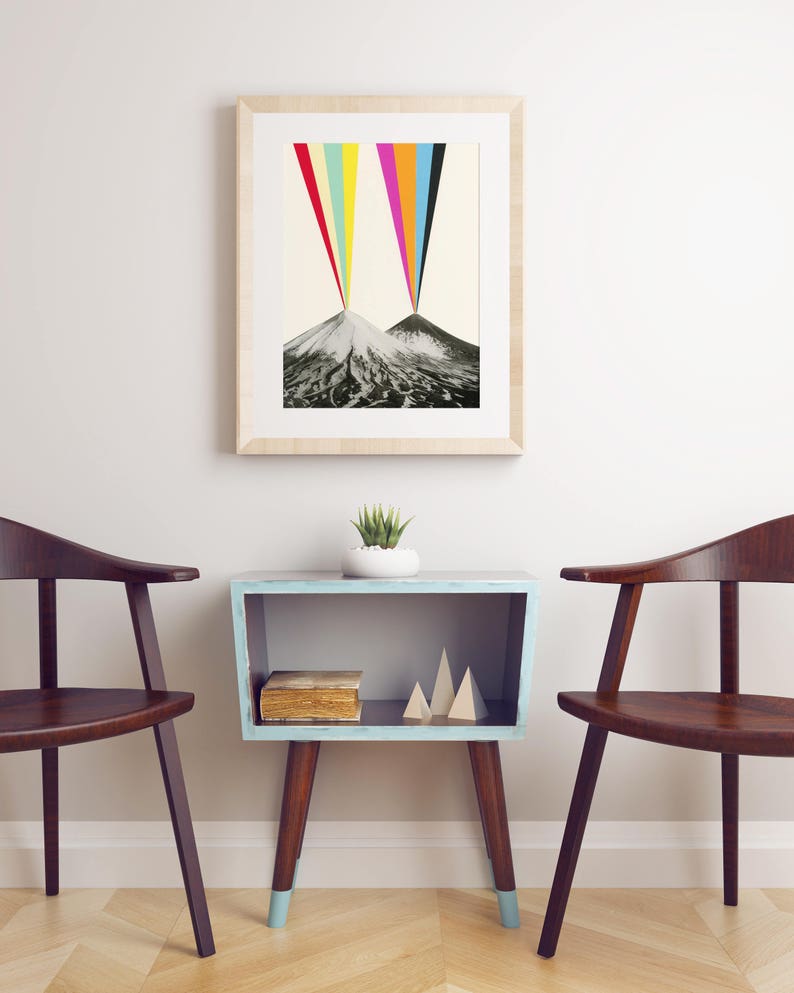 Puede incluir: Una impresi&oacute;n enmarcada de dos monta&ntilde;as con un arco&iacute;ris colorido que emana de las cumbres. La impresi&oacute;n est&aacute; colgada en una pared blanca sobre una mesa auxiliar azul claro con un libro y formas de madera decorativas. Dos sillas de madera est&aacute;n a cada lado de la mesa.