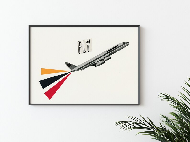 May include: A framed print of a black and white airplane with the word "FLY" in a black rectangle on a white background. The airplane is flying upwards and has a red, black, and orange trail behind it.
