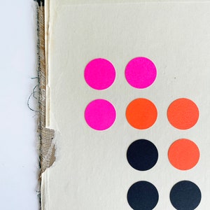 K&ouml;nnte beinhalten: Abstrakte Komposition mit zerrissenem Papierhintergrund und dunkelgr&uuml;nem Rand. Helle pinkfarbene, orangefarbene und schwarze runde Aufkleber sind in einem Muster auf dem Papier angeordnet und bilden ein farbenfrohes, modernes Design.