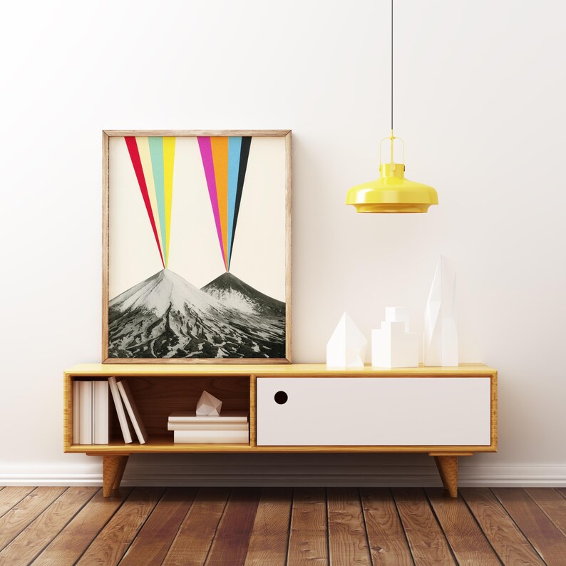Puede incluir: Una impresi&oacute;n enmarcada de una escena de monta&ntilde;a abstracta colorida con un efecto arco&iacute;ris. La impresi&oacute;n se muestra en un estante de madera con un caj&oacute;n blanco y una luz colgante amarilla arriba.