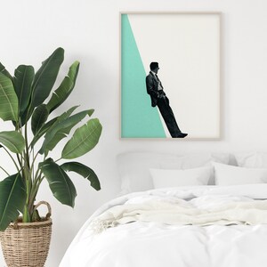 May include: A framed print of a man in a suit sitting on a diagonal line against a light blue background.