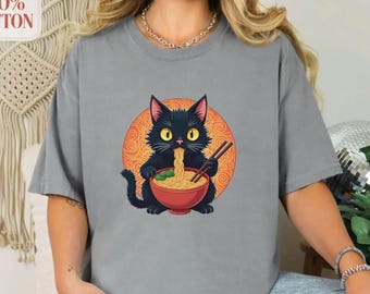 May include: Gray t-shirt featuring a black cat eating ramen from a red bowl with chopsticks. The cat is set against an orange circle background. The shirt is made of 100% cotton.