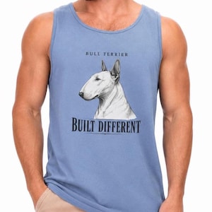 May include: A dusty blue sleeveless tank top featuring a graphic illustration of a white Bull Terrier dog. Above the dog, the text reads BULL TERRIER, and below the dog, the text reads BUILT DIFFERENT in a bold, dark, serif font.