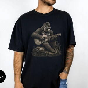 Detailed gorilla playing acoustic guitar while sitting on a rock, vintage engraving artwork for music lovers and guitar players.