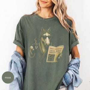 Vintage engraved horse wearing sunglasses and a robe while reading a newspaper and holding a steaming coffee mug. Humorous horse lover design featuring the headline “Local Horse Doesn't Care” in an antique newspaper style. Detailed equestrian artwork with a relaxed, unbothered attitude.