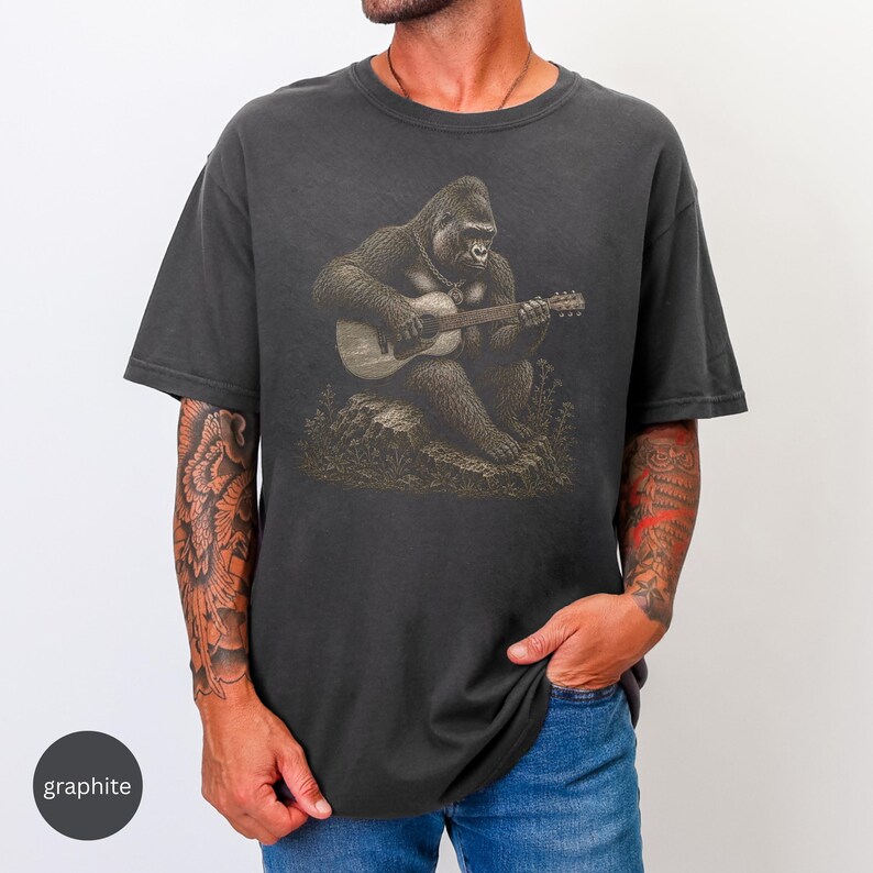 Detailed gorilla playing acoustic guitar shirt design, vintage engraved wildlife musician artwork seated on a rock with necklace.