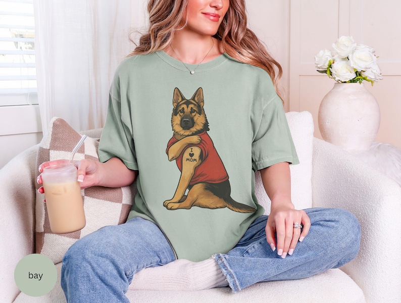 German Shepherd dog illustration wearing a red shirt, lifting sleeve to reveal “I love mom” tattoo, vintage style retro pet graphic, bold clean lines, centered composition, perfect for dog lovers and animal themed apparel designs