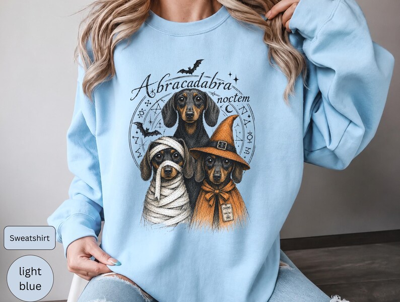 Dachshund Halloween long sleeve and sweatshirt design with three black and tan dogs, mummy wraps, orange witch hat, bats and spell symbols.