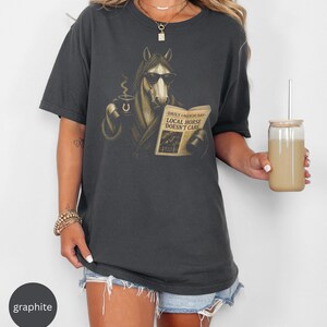 Vintage engraved horse wearing sunglasses and a robe while reading a newspaper and holding a steaming coffee mug. Humorous horse lover design featuring the headline “Local Horse Doesn't Care” in an antique newspaper style. Detailed equestrian artwork with a relaxed, unbothered attitude.