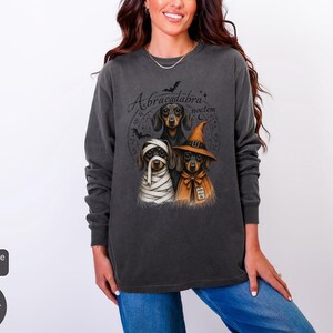 Dachshund Halloween long sleeve and sweatshirt design with three black and tan dogs, mummy wraps, orange witch hat, bats and spell symbols.