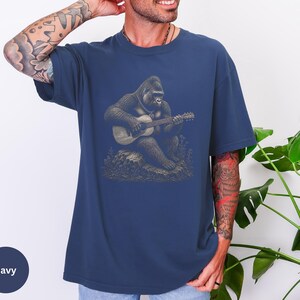 Vintage engraving style gorilla playing an acoustic guitar while seated on a rock, detailed wildlife musician illustration with chain necklace.