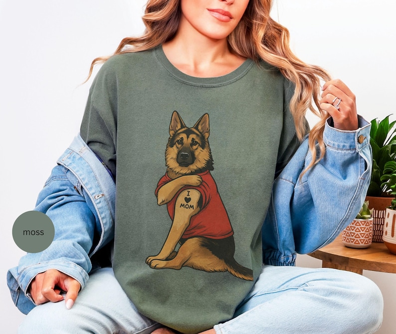 German Shepherd dog illustration wearing a red shirt, lifting sleeve to reveal “I love mom” tattoo, vintage style retro pet graphic, bold clean lines, centered composition, perfect for dog lovers and animal themed apparel designs