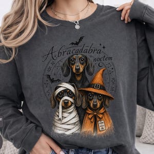 Dachshund Halloween long sleeve and sweatshirt design with three black and tan dogs, mummy wraps, orange witch hat, bats and spell symbols.