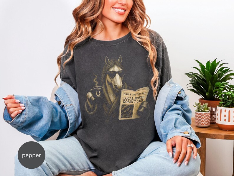 Vintage engraved horse wearing sunglasses and a robe while reading a newspaper and holding a steaming coffee mug. Humorous horse lover design featuring the headline “Local Horse Doesn't Care” in an antique newspaper style. Detailed equestrian artwork with a relaxed, unbothered attitude.