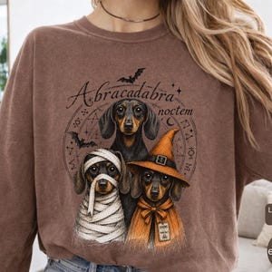 Dachshund Halloween long sleeve and sweatshirt design with three black and tan dogs, mummy wraps, orange witch hat, bats and spell symbols.
