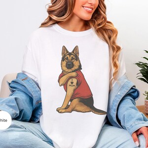 German Shepherd dog illustration wearing a red shirt, lifting sleeve to reveal “I love mom” tattoo, vintage style retro pet graphic, bold clean lines, centered composition, perfect for dog lovers and animal themed apparel designs