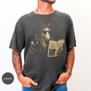 Vintage engraved horse wearing sunglasses and a robe while reading a newspaper and holding a steaming coffee mug. Humorous horse lover design featuring the headline “Local Horse Doesn't Care” in an antique newspaper style. Detailed equestrian artwork with a relaxed, unbothered attitude.