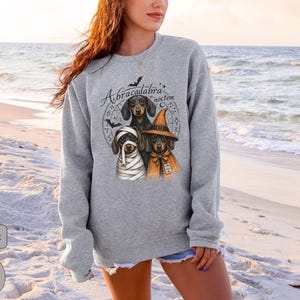 Dachshund Halloween long sleeve and sweatshirt design with three black and tan dogs, mummy wraps, orange witch hat, bats and spell symbols.
