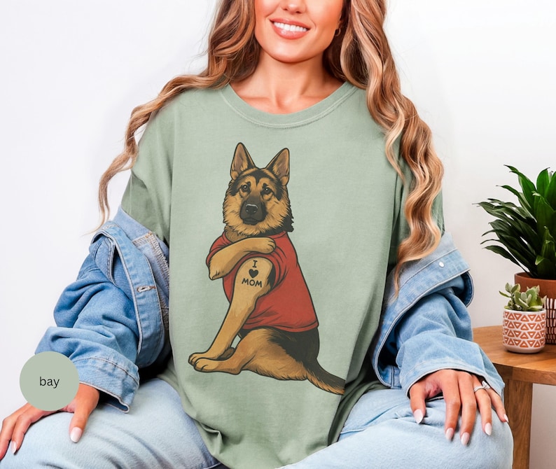 German Shepherd dog illustration wearing a red shirt, lifting sleeve to reveal “I love mom” tattoo, vintage style retro pet graphic, bold clean lines, centered composition, perfect for dog lovers and animal themed apparel designs